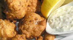 fried food with dipping sauce on plate next to lemon wedges and sour kraut