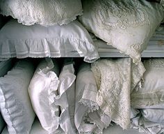 many white pillows and blankets stacked on top of each other