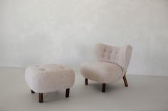 two chairs and a footstool in front of a white wall