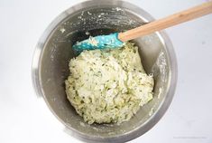 a wooden spoon in a metal bowl filled with food