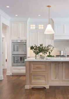 a large kitchen with white cabinets and wood flooring, along with an island in the middle