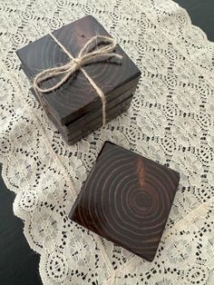 two square wooden coasters tied with twine on a lace doily next to each other