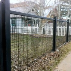 a black metal fence in front of a house with grass and leaves on the ground