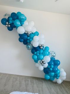 blue and white balloons are hanging from the wall