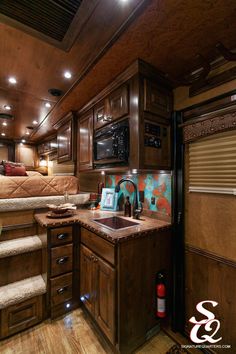 a kitchen with wooden cabinets and stairs leading up to the bed in this motor home