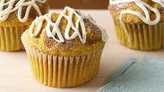 three cupcakes with icing on top sitting on a table