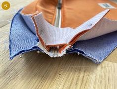 an orange and blue piece of cloth with holes in the middle on a wooden surface