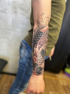 a person with a tattoo on their arm holding something in the other hand and looking at it