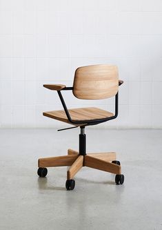 an office chair made out of wood and metal with wheels on the back, in front of a white brick wall