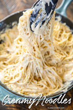 the noodles are being stirred with a ladle in a skillet on top of a wooden table