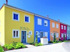 a row of multi - colored houses on a street in front of a blue sky