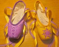 two pairs of purple and yellow ballet shoes on a wooden table with ribbons around them