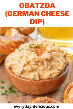 a wooden bowl filled with cheese dip next to pretzels