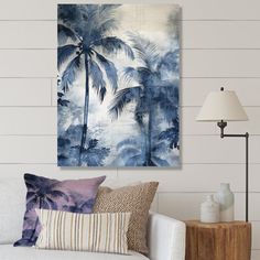 a living room with a white couch and palm trees on the wall in front of it