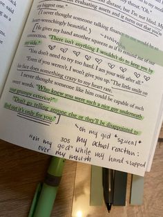 an open book with writing on it and a green pen next to it, sitting on top of a wooden table