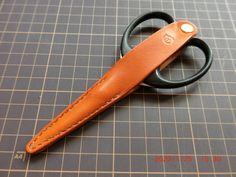 a pair of scissors sitting on top of a table next to a piece of leather