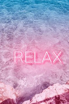 the word relax written in pink neon light on top of water with rocks and blue sky