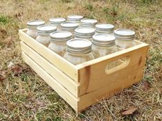 a wooden box filled with mason jars sitting on top of grass