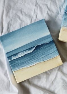 two pieces of art that look like paintings on canvases are sitting on a bed