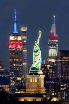 the statue of liberty is lit up in red, white and blue for the new york city skyline