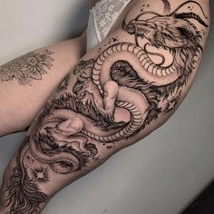 a woman's leg with tattoos on it and a dragon tattooed on the side