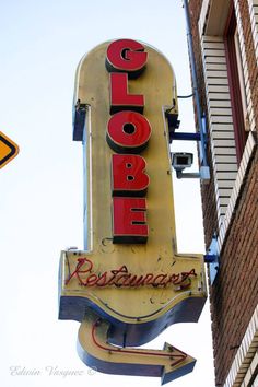 a close up of a neon sign on the side of a building with a sky background