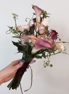 a person holding a bouquet of flowers in their hand with the stems still attached to it