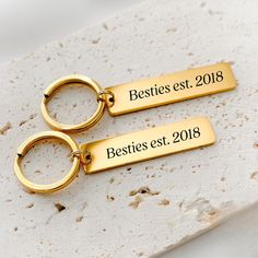 two gold keychains with the names besties est, and besties est on them