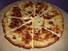 a cheese pizza cut into four pieces on a wooden board