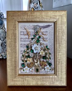 a christmas tree made out of old sheet music and other ornaments in a gold frame