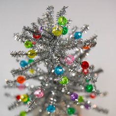 a silver christmas tree with multicolored ornaments