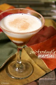 a drink in a glass on top of a table next to a napkin and place mat