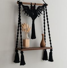 a wooden shelf with two vases on it and some tassels hanging from the wall