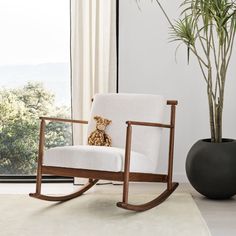 a rocking chair with a teddy bear sitting on it in front of a large window