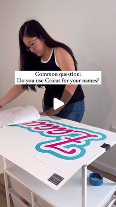 a woman standing over a table with a sign on it that reads common question do you use cricut for your names?