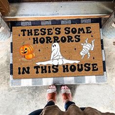 someone standing in front of a door mat that says, these's some horrors in this house