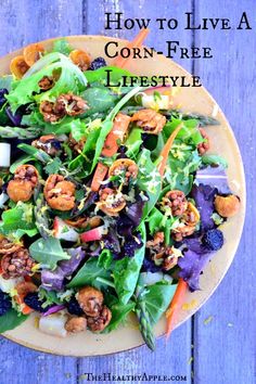 a salad with lettuce, carrots and nuts on a yellow plate against a blue wooden background