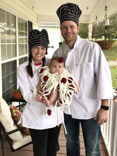 a man and woman holding a baby dressed in chef's hats while standing on a porch