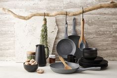 various pots and pans are arranged on a table next to a driftwood branch