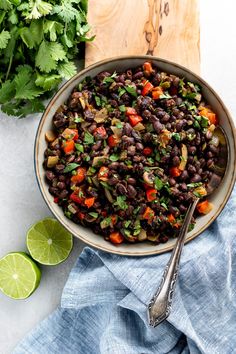 a bowl filled with black beans, carrots and cilantro on top of a wooden cutting board