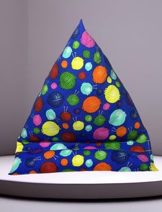 a blue hat with multicolored balls on it sitting on top of a white plate