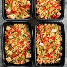 four black trays filled with rice and vegetables on top of a gray countertop