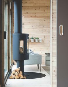 a wood burning stove in the corner of a room with wooden walls and flooring