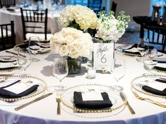 the table is set with white flowers and place settings