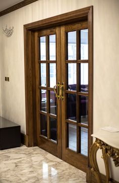 an open wooden door in a room with marble flooring