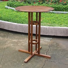 a wooden table sitting on top of a cement floor next to a lush green field