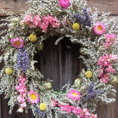 a wreath made out of flowers on top of a wooden door frame with purple and yellow thistles