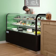 a man standing behind a display case filled with cakes