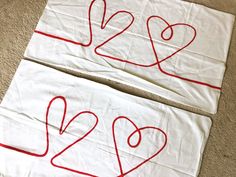 two pieces of white cloth with red thread on them and numbers drawn in the shape of hearts