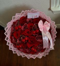 a bouquet of red roses and cherries with a pink bow